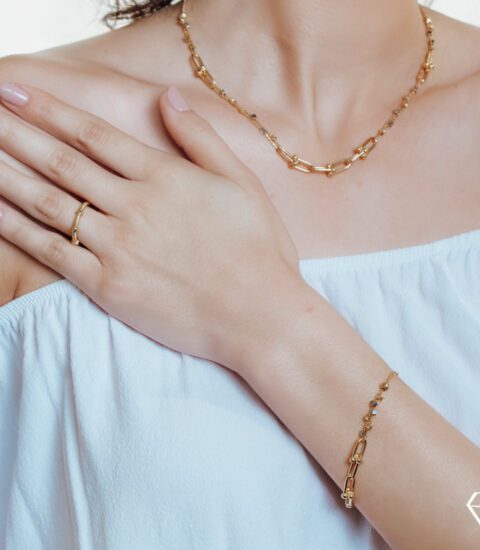 Farah El Khoury Jewelry, image of a woman showcasing golden bracelet and golden necklace
