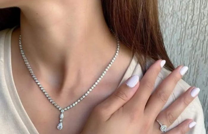 Trois Quart, image of a woman's neck showcasing necklace and ring accessories